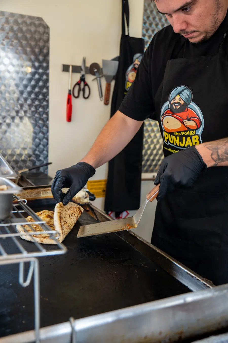 A chef working the griddle inside a street food trailer